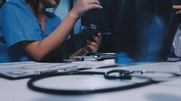 A doctor is working on a laptop while another person looks on video
