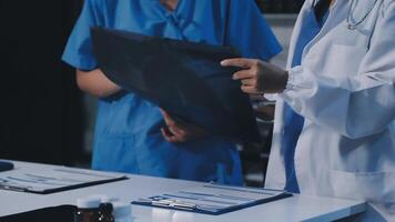 Two doctors are standing around a table with a patient video
