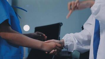 Two doctors shaking hands in front of a computer video