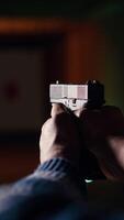 Vertical Man in shooting gallery using firearm, looking at results on moving target. Close up of person training for competitive shooting sport, sharpening skills, checking points scored on bullseye, camera B video