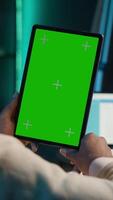 Vertical African american remote worker uses chroma key display on device to work from the comfort of his home, sitting on the sofa in his modern stylish living room. Happy young man on internet. Camera A. video
