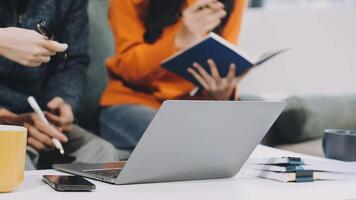 A group of people sitting around a table with a laptop video