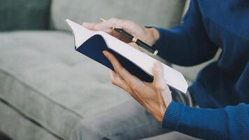 A man is writing in a notebook while sitting on a couch video