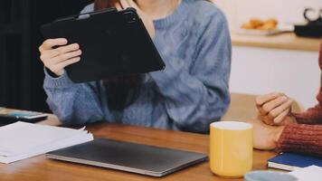 A man and woman sitting at a table with a laptop video