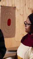 Vertical Shooting gallery safety officer demonstrating how to safely reload pistol and gun to clients, supervising range activities. Firing range expert teaching proper weapon handling and usage, camera B video