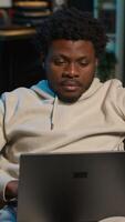 Vertical Freelancer at home focused on online research and surfing the internet, utilizing a laptop for telework and staying connected in a digital world. Browsing the social media on his couch. Camera A. video
