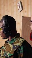 Vertical Portrait of happy army soldiers in shooting gallery looking at targets, comparing points obtained. Cheerful military units testing accuracy in firing range, looking at shot bullseye, camera B video