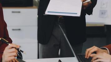 A man is holding a piece of paper while two other people are sitting at a table video
