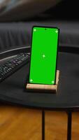 Vertical Black male remote worker laying on the couch next to chroma key display, enjoying leisure and free time for relaxation in his modern loft apartment with neon lights and a smart tv. Camera A. video