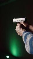 Vertical Shooting range client shoots with pistol, engaging targets at extended range. African american man at shooting ground firing lethal fire weapon, wearing protection equipment, camera A close up video