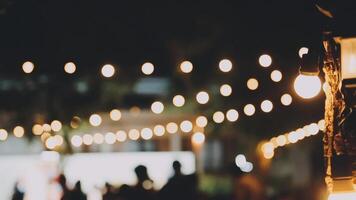 A group of people are standing around a string of lights video