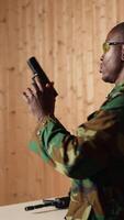 Vertical Soldier in shooting range reloads pistol, shooting target, celebrating after achieving perfect accuracy. Military unit in firing range practices with weapon, cheering after hitting bullseye, camera A video