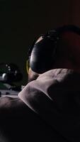 Vertical Man in firing range doing shooting activity with rifle, wearing earmuffs to protect hearing. Person training with semiautomatic weapon, using safety gear to prevent damage from gunshots, camera B video