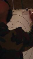 Vertical Man in firing range shooting targets with pistol, wearing earmuffs to protect hearing. Person training with weapon, hitting bullseyes, using safety gear to prevent damage from gunshots, camera A video