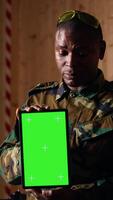 Vertical Soldiers at shooting range do training designed to increase safety and survivability in combat, watching instructional videos on green screen chroma key tablet device presented by commander, camera B