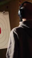 Vertical Firing range customer doing shooting activity with pistol, looking in zooming device to check if he shot bullseye. Person in shooting gallery analyzing targets shot using magnifying lens, camera A video