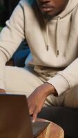 Vertical Confident young man solving daily tasks on a freelance platform at home, answering emails and multitasking. Person staying connected and enjoying the flexibility of working remotely. Camera A. video