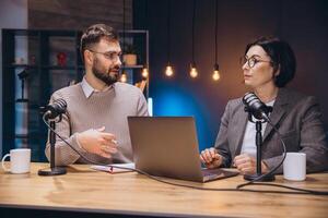 Podcast creators recording audio content, working with laptops and microphones in comfortable home studio setting photo