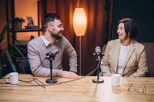 Professional podcasters speaking into microphones, collaborating and smiling during recording session for digital audio broadcast photo