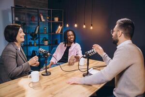 Professional podcast team recording radio show, collaborating and sharing insights during live audio production in soundproofed studio setting photo