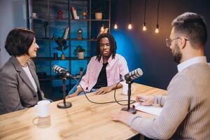Podcasters interviewing a guest in a recording studio, having a conversation and taking notes photo