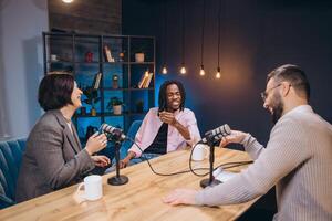 Content creators recording an episode of their podcast in a professional studio, discussing and laughing during a lively conversation photo