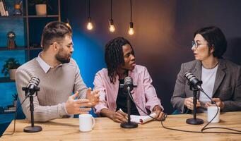 Podcasting team collaborating, speaking into microphones while exchanging professional insights during live recording session photo