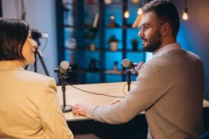Podcasters discussing animatedly while recording in soundproofed studio, professional microphones and mixing board visible in background photo