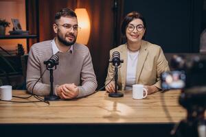 Two content creators are recording a podcast in a professional studio, using microphones and a camera photo