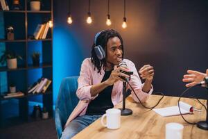 Podcaster speaking into microphone, wearing headphones, capturing dynamic interview in sleek recording studio with professional broadcasting gear photo