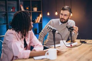 Podcasters conversing while recording audio in professional broadcasting studio photo