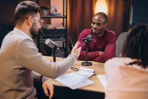 Two radio hosts interviewing a guest in a professional podcast studio, discussing and recording audio content photo