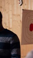 Vertical Shooting range safety officer demonstrating how to safely reload pistol to customers based on industry regulations. Firing range staff member teaching proper handgun handling, camera B video