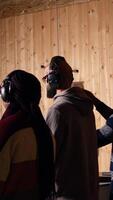 Vertical Group of shooting range customers shooting targets with pistols and rifles, learning to operate weapons in close quarters. Friends at shooting ground firing lethal fire handguns together, camera A video
