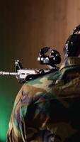 Vertical Portrait of happy military personnel using tactical operations equipment, shooting assault rifle. Smiling man in firing range preparing for mission, practicing with semiautomatic weapon, camera B video
