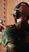 Vertical Happy military personnel in firing range shoots targets with handgun, satisfied after achieving positive result. Joyous soldier training with firearm exults after accurately hitting bullseye, camera B video