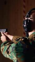 Vertical Cheerful army unit in firing range shooting targets with pistol pleased after achieving positive result. Excited soldier training with weapon thrilled after accurately hitting bullseye, camera B video