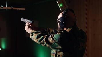 Portrait of cheerful military unit using tactical operations equipment, shooting pistol. Joyous army soldier in firing range preparing for mission, practicing with weapon, camera B video