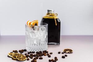 Cold brew coffee in a bottle with transparent glass full of ice on light gray background photo