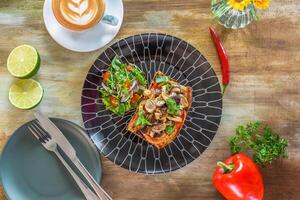 Mushrooms on toast with hummus, garlic butter, thyme and truffle oil on wooden table with fork, knife and lemonade drink photo