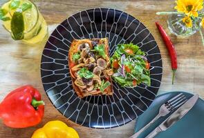 Mushrooms on the toast with hummus, garlic butter, thyme and truffle oil on wooden table with fork, knife and lemonade drink photo