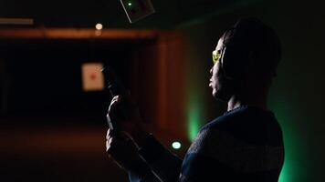 Firing range customer doing shooting activity with pistol, looking in zooming device to check if he shot bullseye. Person in shooting gallery analyzing targets shot using magnifying lens, camera B video