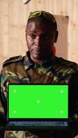 Vertical Team of military units at shooting range watching on isolated screen laptop to learn necessary combat skills. Army soldiers looking at instructions on mockup notebook during training, camera B video