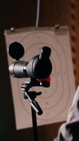 Vertical Friends in firing range doing recreational shooting, using magnifying lens to see targets. People training with handguns, sharpening skills, zooming to check points scored on bullseyes, camera B video
