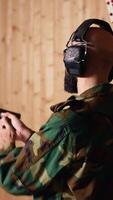 Vertical Army soldier in shooting range reloads pistol, shooting target, testing accuracy, looking at results. Military man in firing range practices with weapon, checking to see if he shot bullseye, camera B video