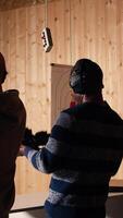 Vertical Friends in firing range doing recreational shooting, pressing mechanism to recall paper targets. People training with handguns, sharpening skills, checking points scored on bullseyes, camera A video