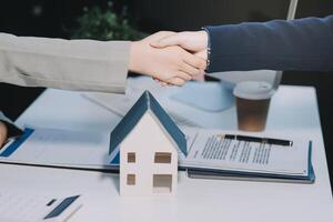 Two people shaking hands over a house model photo