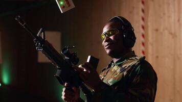 Portrait of cheerful soldier doing training in shooting range, reloading rifle. Joyous military unit in firing range practicing with semiautomatic weapons, wearing protective equipment, camera B video