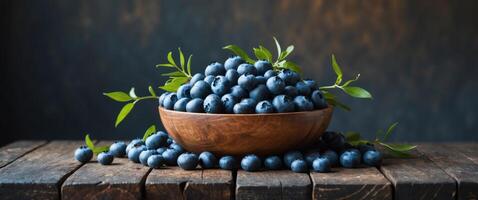 Fresh blueberries in a rustic wooden bowl on an aged table with a dark background highlighting natural textures and empty space for text. photo