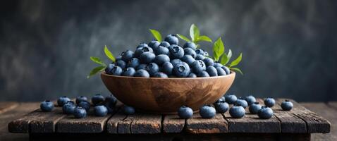 Fresh blueberries in a rustic wooden bowl on an aged table with a dark background highlighting natural textures and empty space for text photo